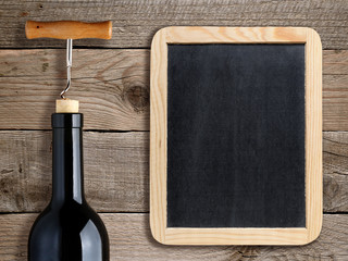 Bottle of wine and blank blackboard on wooden background
