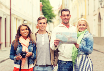 group of smiling friends with map and photocamera