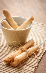 Breadsticks in napkin on wooden background.