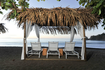 Three lounge chairs on a beach covered