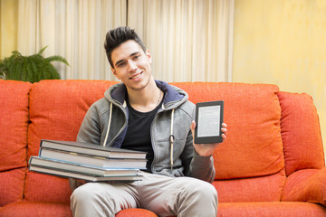 Fototapeta premium Young man showing difference between ebook reader and heavy