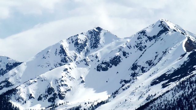 Zoom in on snow capped Rocky Mountain peaks