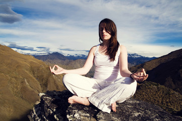 Naklejka na ściany i meble Young Woman Meditating in the Wilderness with Beautiful Mountain