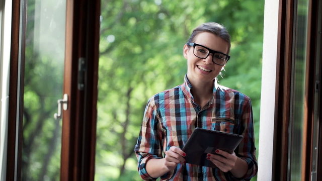 Portrait of happy geek woman with tablet computer on balcony