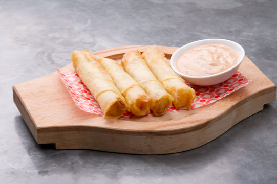 Cheese rolls plate with cocktail sauce served on a wooden plate