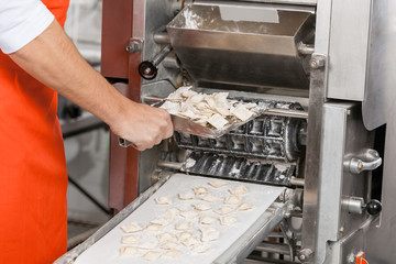 Male Chef Removing Ravioli Pasta From Machine