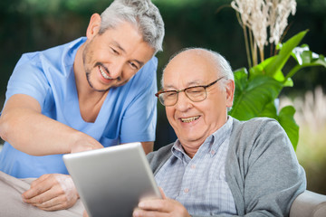 Nurse And Senior Man Enjoying While Using Tablet Computer