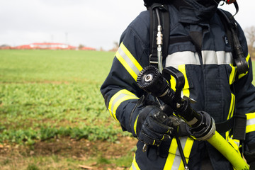 Feuerwehrmann im Einsatz mit Löschschlauch