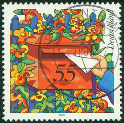 stamp shows hand depositing a letter to a mailbox