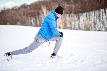 Fitness concept - male athlete stretching on snow