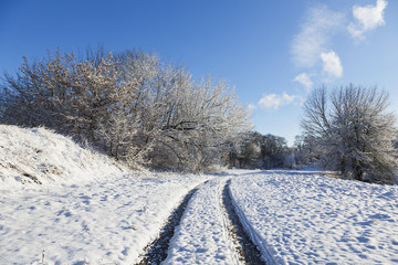 Fototapeta na wymiar Countryside road through winter field on a sunny day