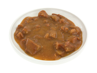 Plate of roast beef in gravy on a white background