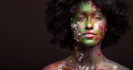 Close up portrait of young woman in afro wig and face art