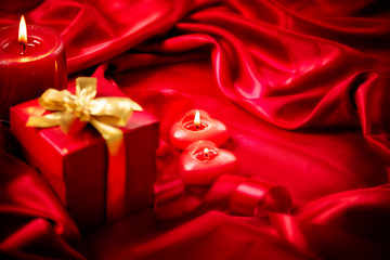 Valentine red heart shaped candles and gift on red silk