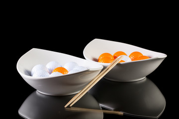 Two white ceramics bowls with golf balls on the glass table