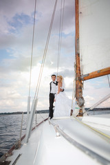 Fototapeta premium Happy bride and groom hugging on a yacht