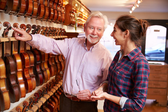Salesman Advising Customer Buying Violin