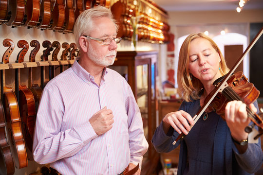 Customer Trying Out Violin In Music Store