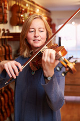 Customer Trying Out Violin In Music Store