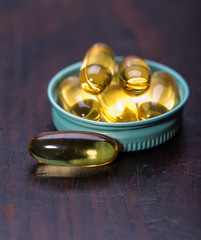 Cod liver oil omega 3 gel capsules isolated on wooden background