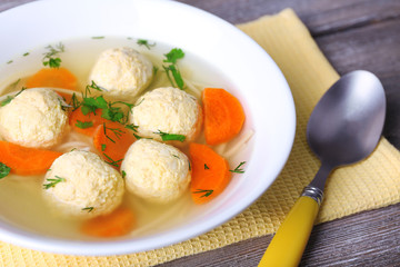 Soup with meatballs and noodles in bowl on wooden background