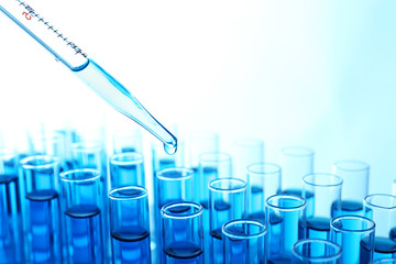 Pipette adding blue fluid to the one of test-tubes