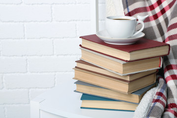 Pile of books with cup and plaid