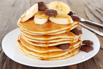 Stack of delicious pancakes with chocolate, honey and slices of