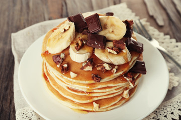 Stack of delicious pancakes with chocolate, honey, nuts and