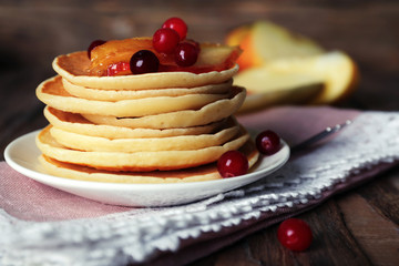 Stack of delicious pancakes with slices of apple and berries