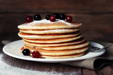 Stack of delicious pancakes with powdered sugar and berries