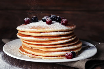Stack of delicious pancakes with powdered sugar and berries