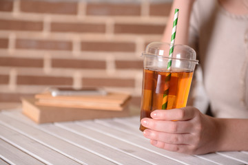 Female sitting at wooden table with fast food closed cup of