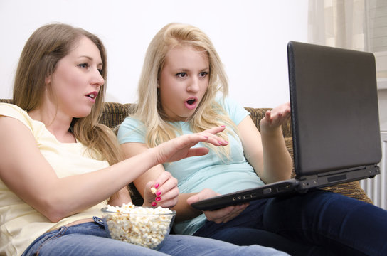 Two girlfriends shockingly pointing at laptop screen