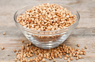 Dry buckwheat groats in a bowl on wooden table