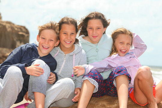 portrait of group of happy children outdoors with ocean and sky in background
