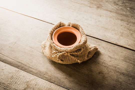 Clay pot in sackcloth bags on wooden background
