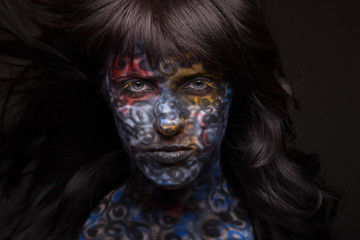 Brunette woman in dark colourful paint on skin. Face art.