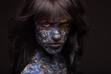 Brunette woman in dark colourful paint on skin. Face art.