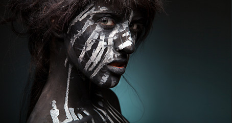 dark portrait of woman in black paint with white smudges 