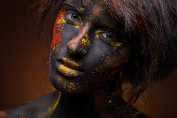 dark portrait of woman in black paint with yellow smudges