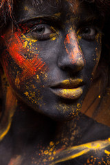 Fototapeta premium dark portrait of woman in black paint with yellow smudges