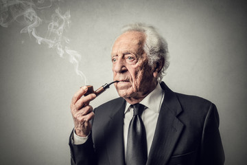 Elderly businessman smoking the pipe - obrazy, fototapety, plakaty