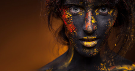 dark portrait of woman in black paint with yellow smudges