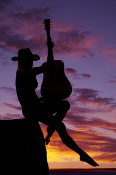 silhouette of a woman with a guitar sit leg out