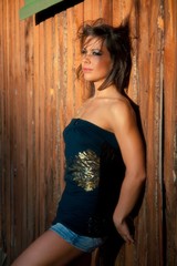 Fototapeta premium Young woman portrait near the wall in sunshine