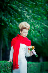 Bride in a white dress and a long red scarf on the nature