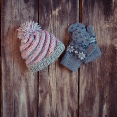 Fototapeta na wymiar grey knitted winter gloves and hat on wooden boards