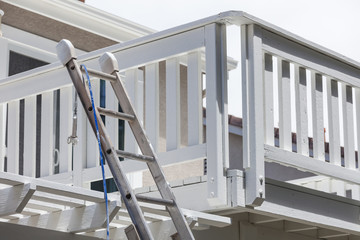 Naklejka premium Construction Ladder and Painting Hose Leaning on House Deck