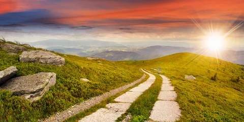 Poster road on a hillside near mountain peak at sunset © Pellinni